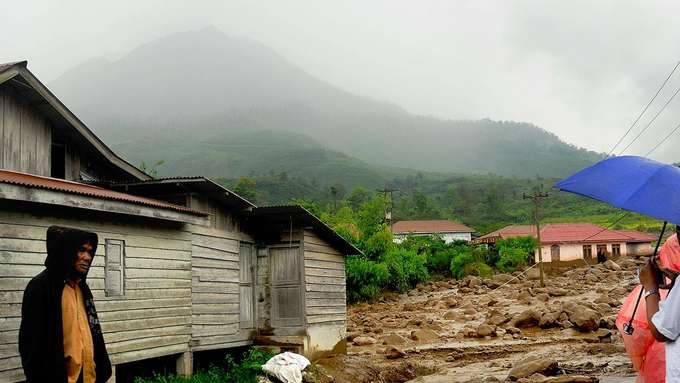 Vulkanismus und Wetter Menschen stehen vor einem Haus im Regen, Schlamm am Boden