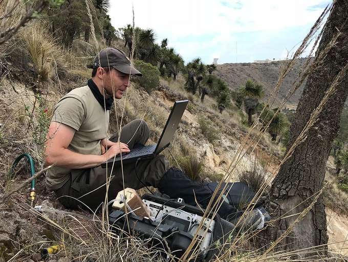 Vulkanismus und Geothermie Wissenschaftler sitzt mit Laptop im Gelände für Feldmessungen