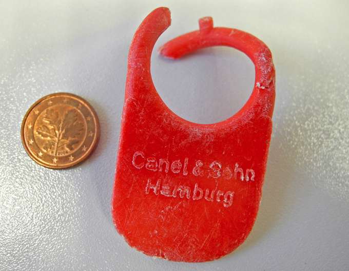 Fundstück: Auf Spitzbergen wurden an den Stränden Plastikteile aus Europa gefunden. (Foto: M. Bergmann/AWI) Foto rotes Plastikteil neben Münze gefunden am Strand von Spitzbergen